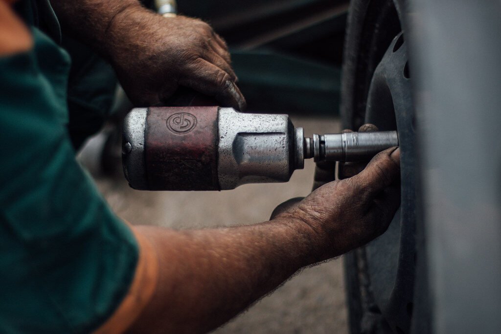 Tire technician using an impact wrench on a wheel