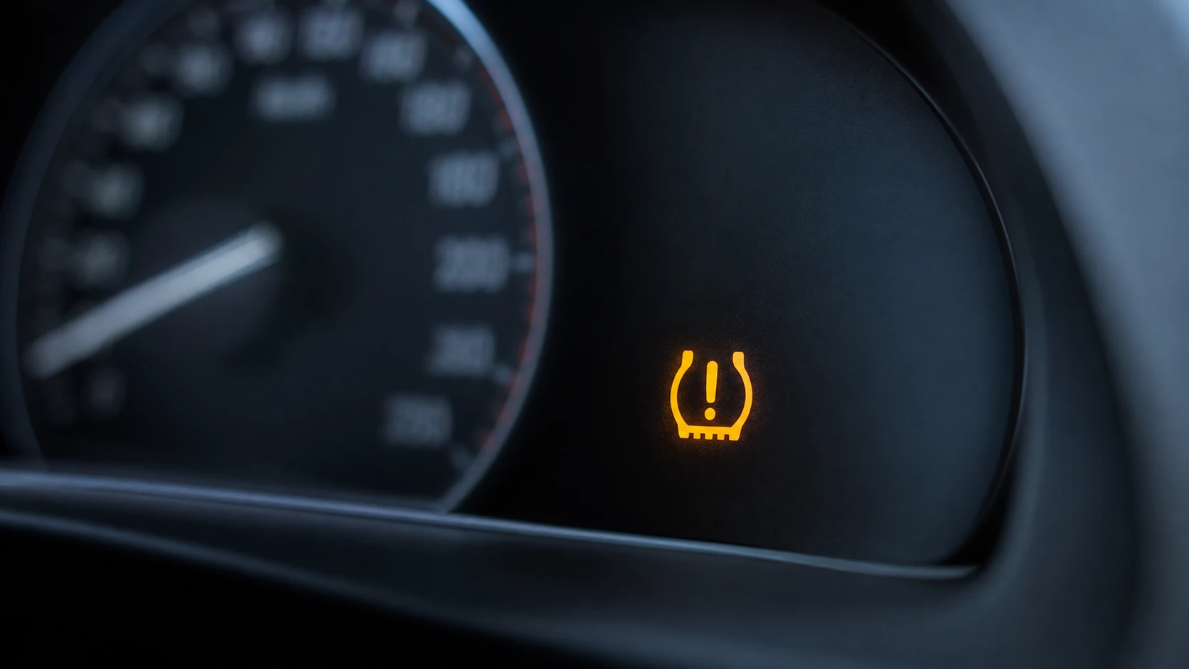 Amber TPMS tire pressure warning light glowing on a modern car dashboard.